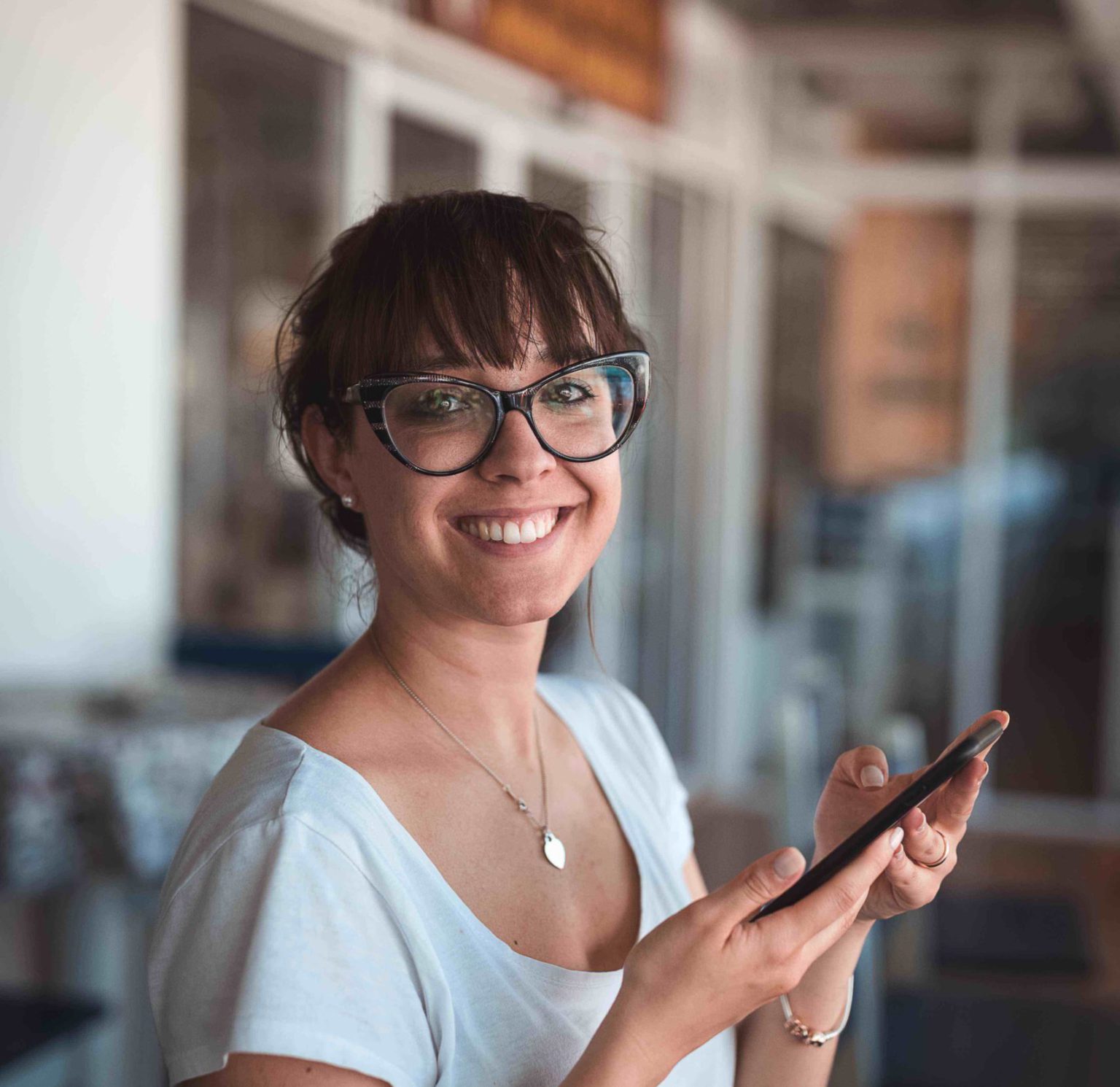 Photo of a woman smiling at the camera and holding a smart phone